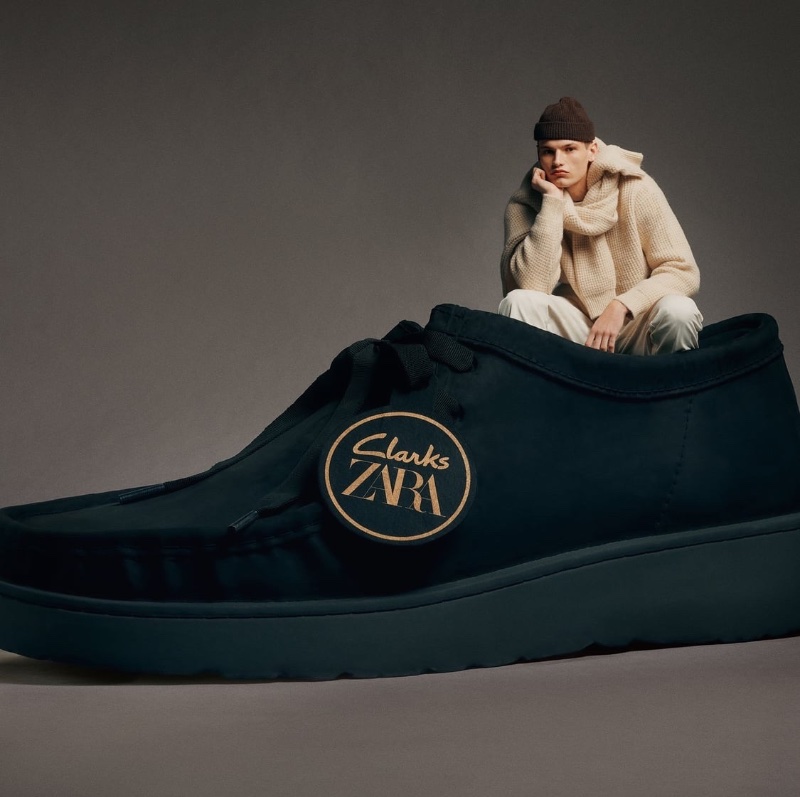 Model Louis Göckenjan poses inside an oversized leather shoe for the Clarks x Zara collection.