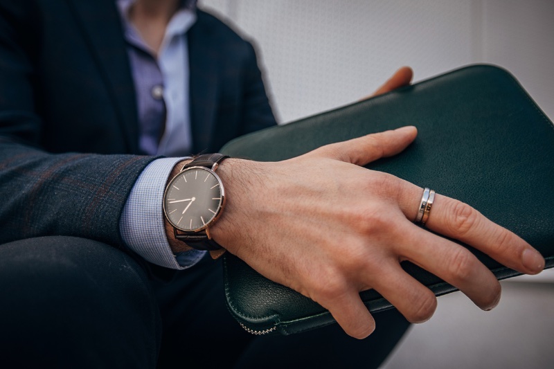 Man Wearing Watch Wedding Band Holding Leather Accessory