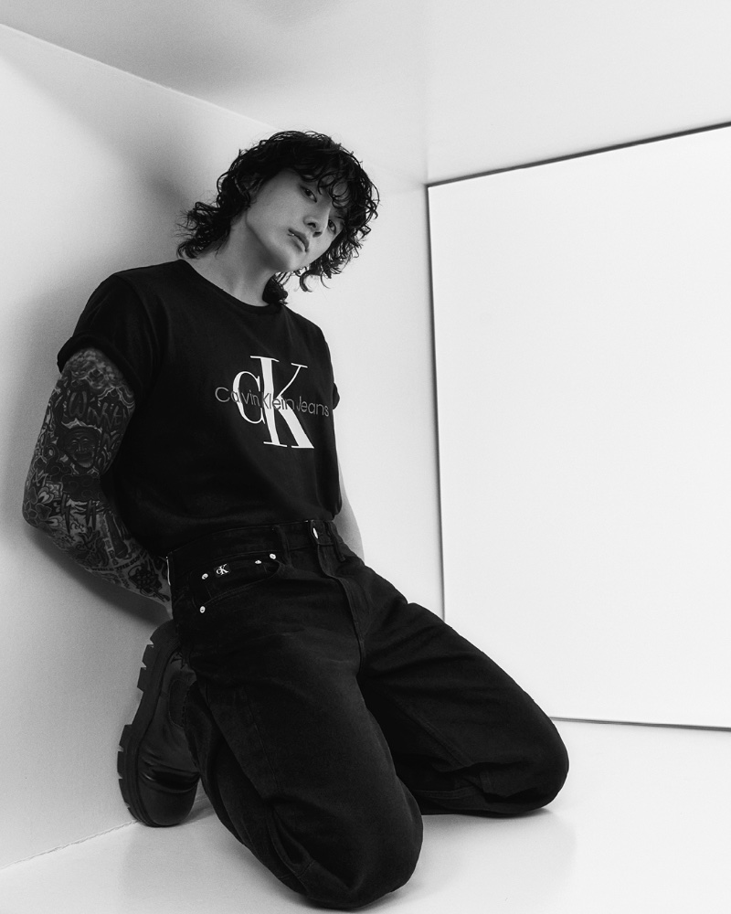 Dressed in black, Jung Kook wears a black Monogram Tee with Standard Straight Black Jeans for Calvin Klein's spring-summer 2023 campaign.