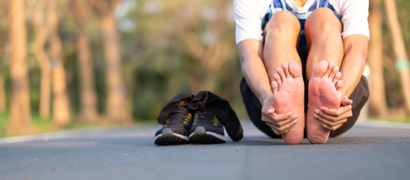 Man Holding Feet Next to Sneakers » The Life-Changing Benefits of Shoes with Arch Support Man Holding Feet Next to Sneakers