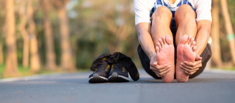 Man Holding Feet Next to Sneakers