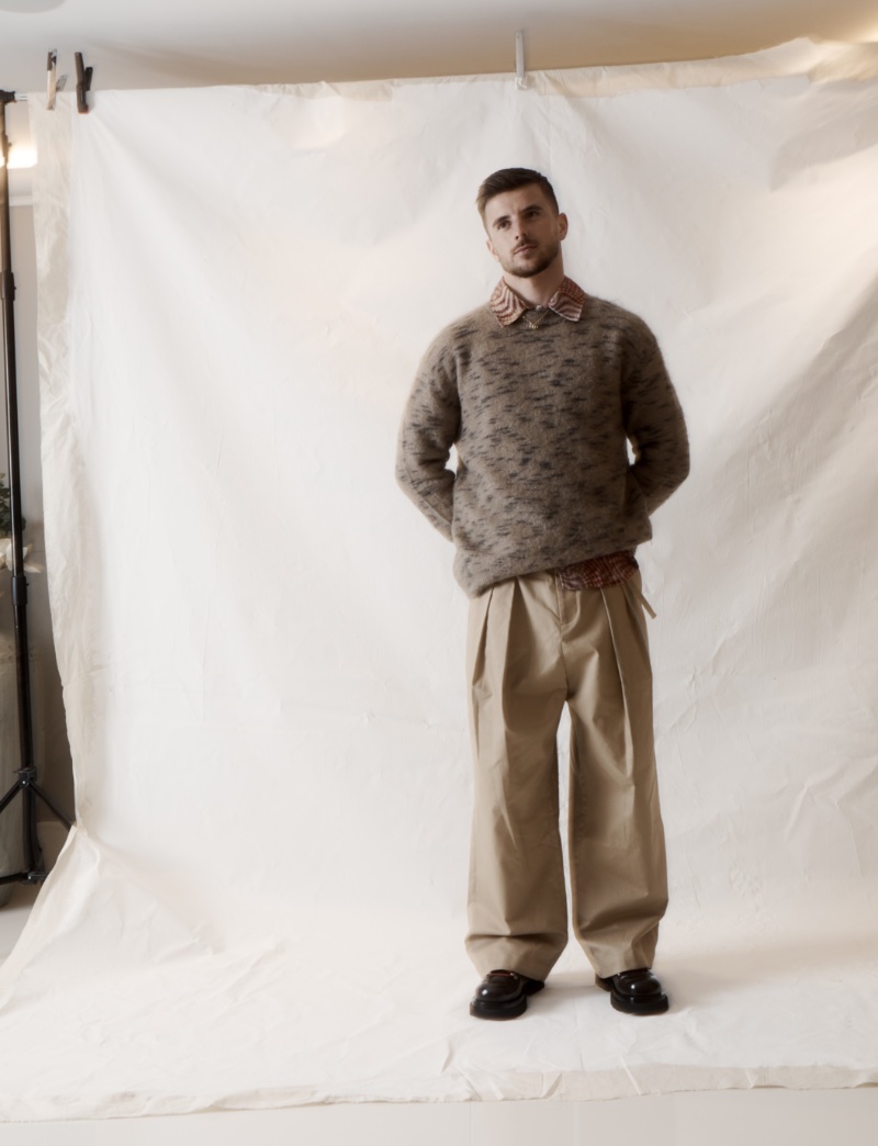 Posing for photos, Mason Mount wears an Our Legacy shirt with an Acne Studios sweater, JW Anderson trousers, and Bottega Veneta shoes. 