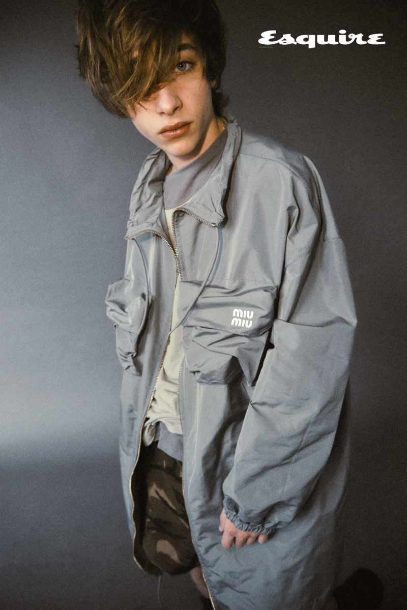 Wearing a sporty look, Raphael Luce slips into a Miu Miu parka with camouflage shorts by Celine Homme.