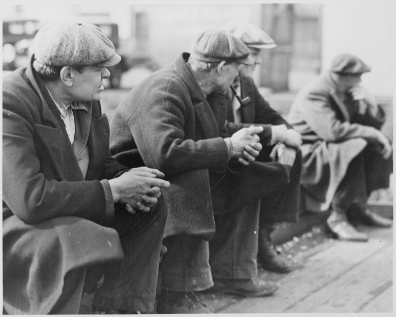 Unemployed men wear flat caps and heavy coats at the New York City docks in 1934. 