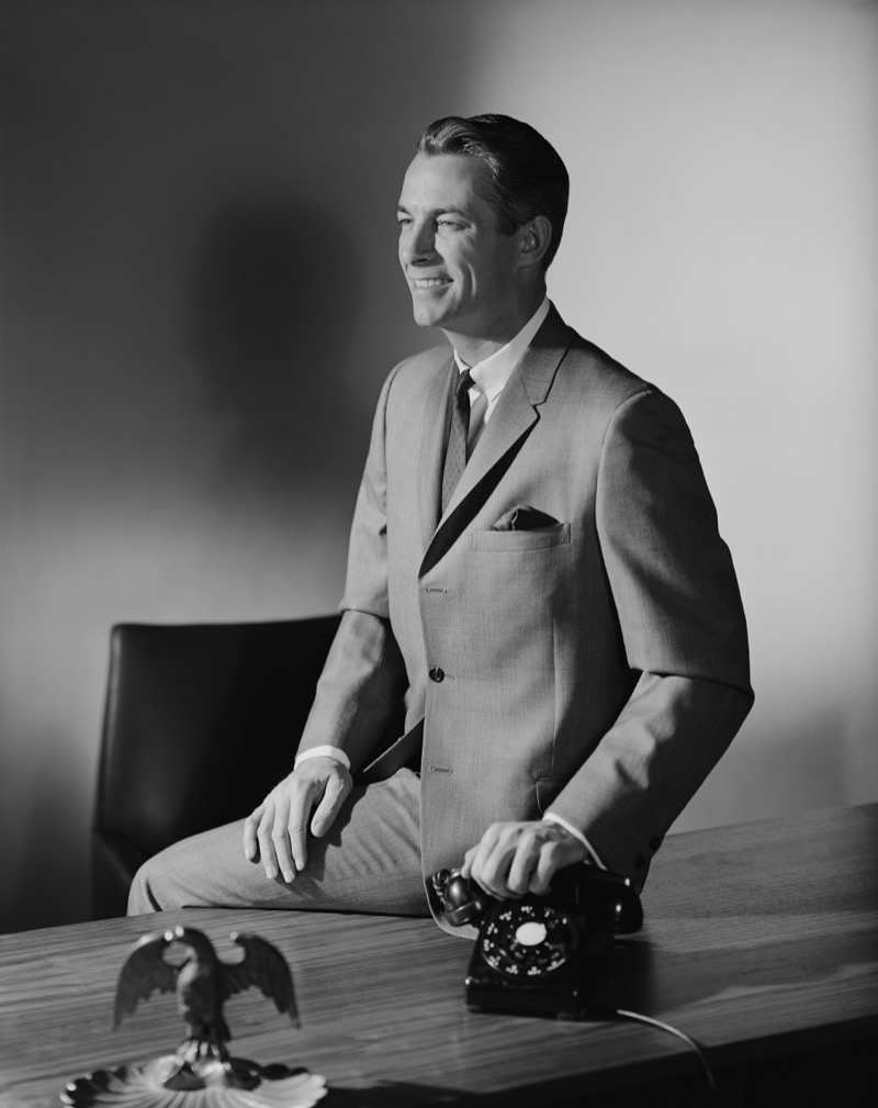 The mid-century company man wears a two-button sack suit with a narrow tie.