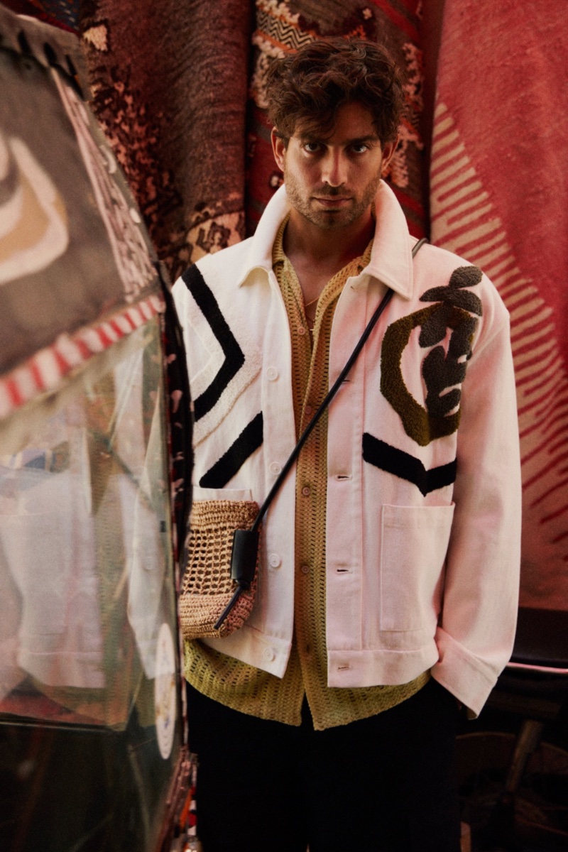 Model Andrew Georgiades dons a mixed textured jacket with a crochet textured shirt, balloon fit pants, and a woven mini crossbody bag by Zara.