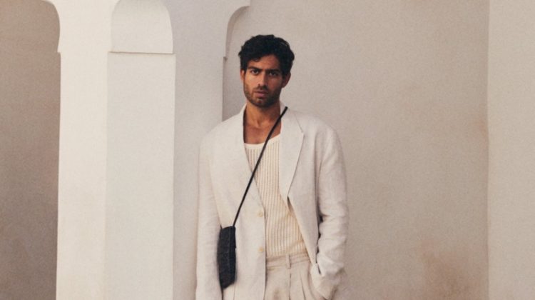 Andrew Georgiades models a Zara linen blazer and trousers with a crochet tank, leather sandals, and a crossbody bag.