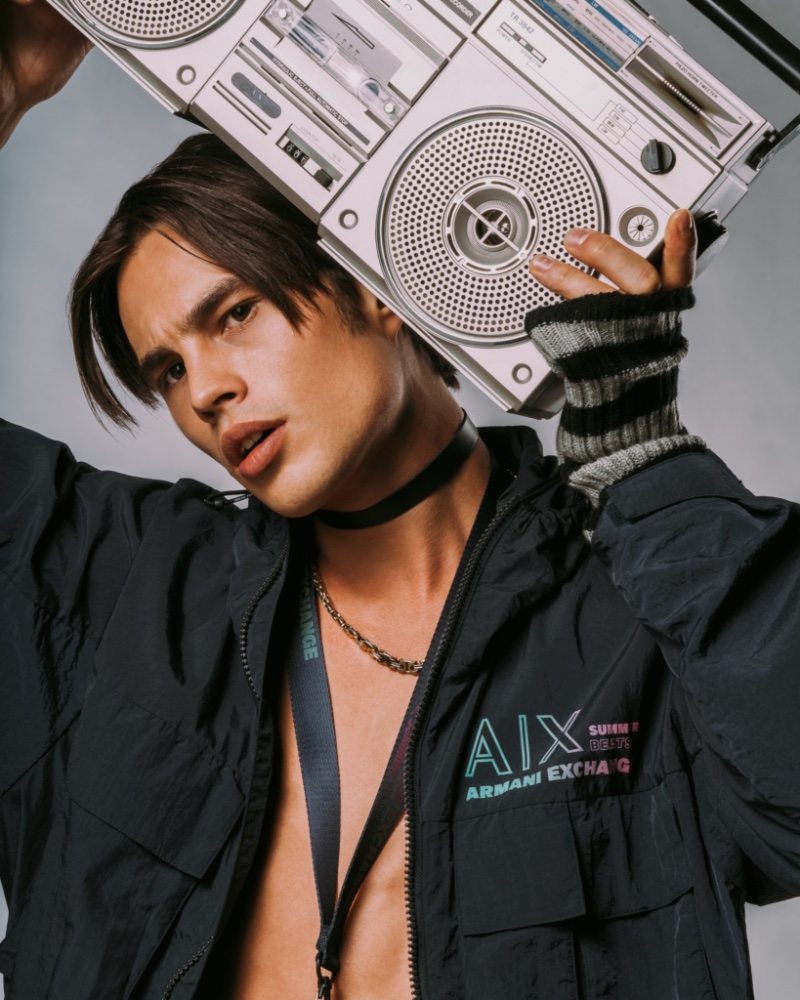 Taking hold of a boombox, Louis Baines rocks an Armani Exchange windbreaker.