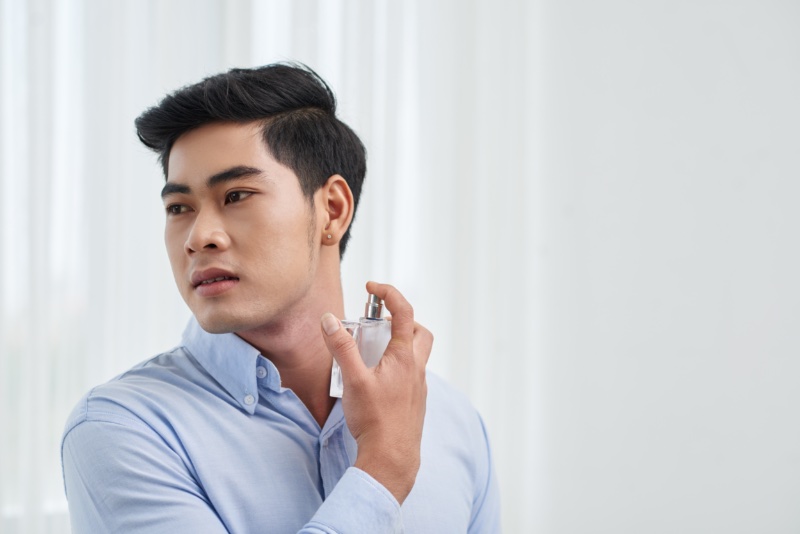 Asian Man Spraying Cologne Dress Shirt » The Art of Scent Layering: A Guide for Gentlemen Asian Man Spraying Cologne Dress Shirt
