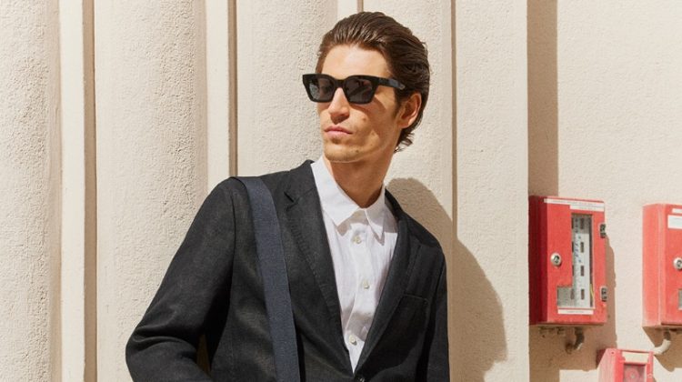 Model Justin Eric Martin wears a short suit with a linen shirt and D-frame sunglasses.