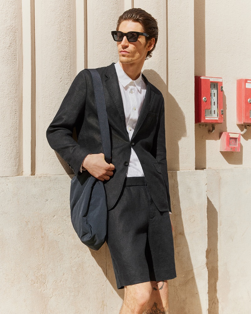 Model Justin Eric Martin wears a short suit with a linen shirt and D-frame sunglasses.