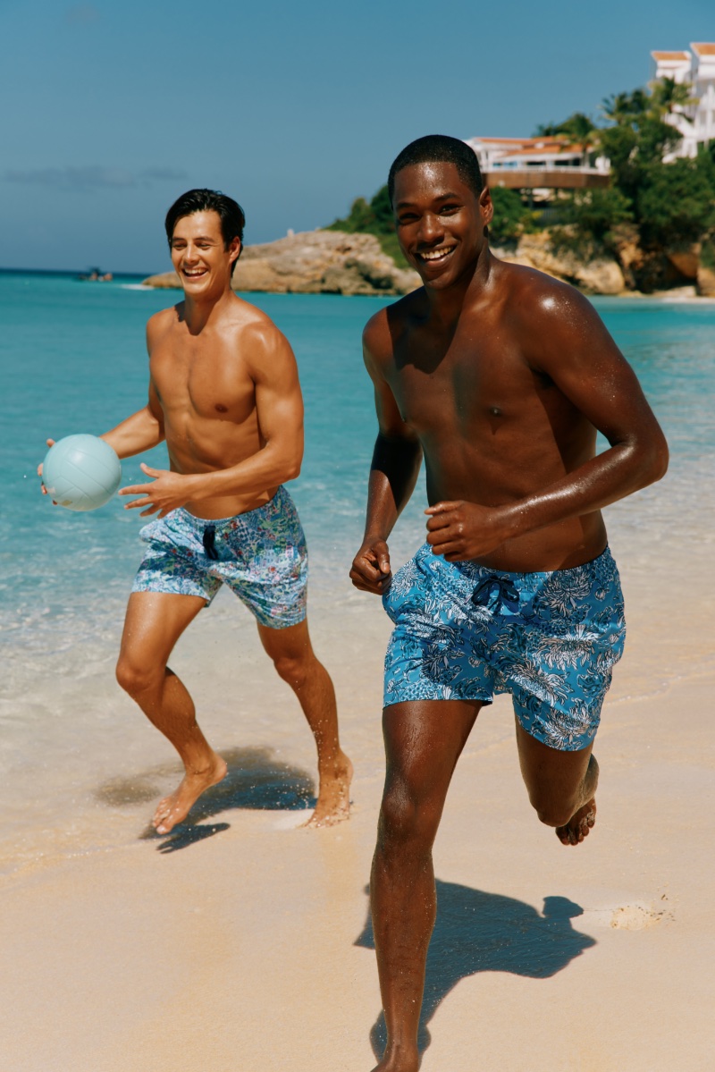 Models Harry Gozzett and Ronald Epps hit the beach in swim trunks from the Lilly Pulitzer x Southern Tide collection.