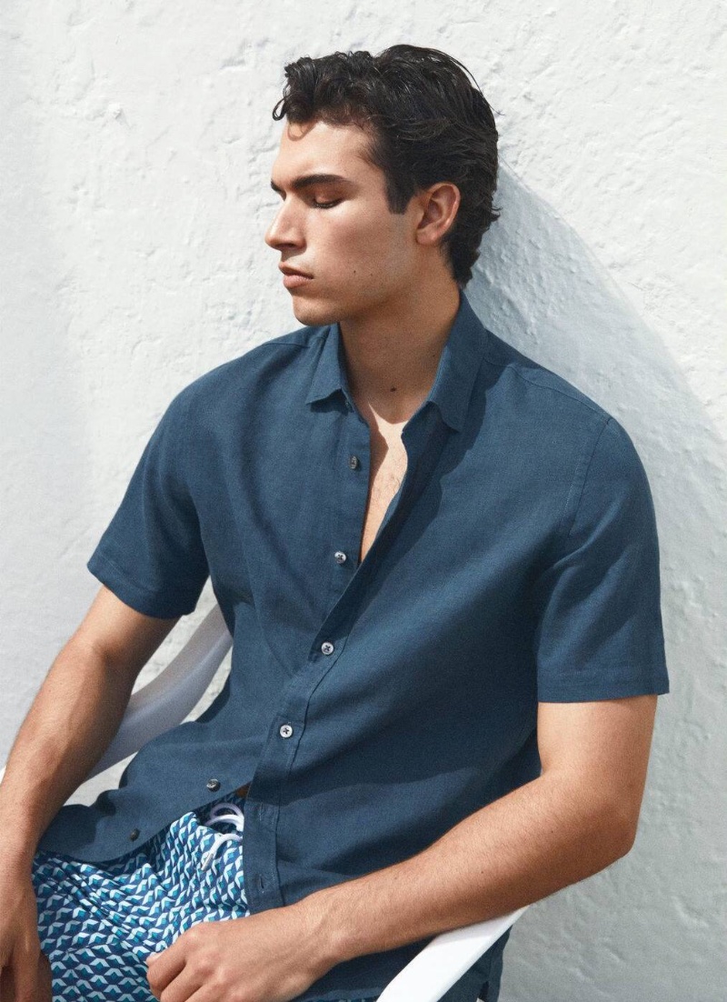 Donning a Mango summer outfit, Balthazar Dib models a short-sleeve linen shirt in navy.