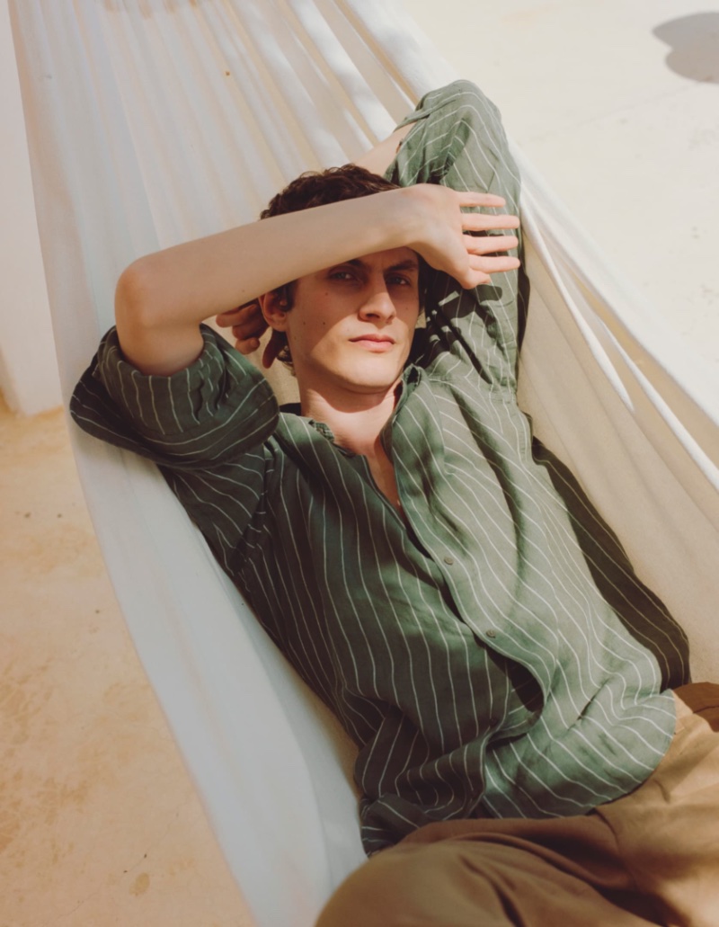 Lounging, Henry Kitcher dons a striped Massimo Dutti shirt.