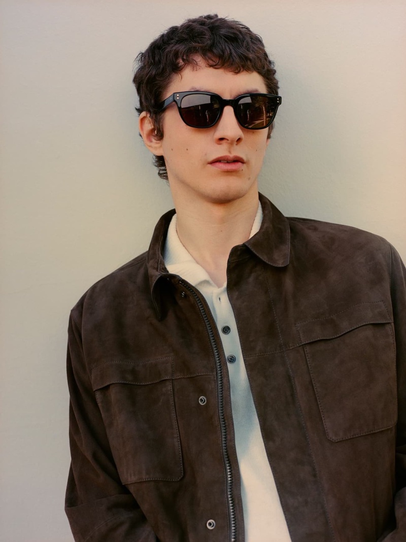 Taking up the spotlight, Henry Kitcher rocks a brown suede jacket over a polo.