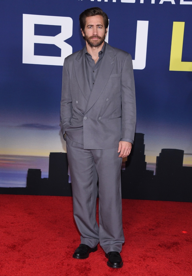 Jake Gyllenhaal subscribes to monochromatic dressing in an oversized double-breasted suit and shirt from Giorgio Armani to attend the Los Angeles premiere of Ambulance.