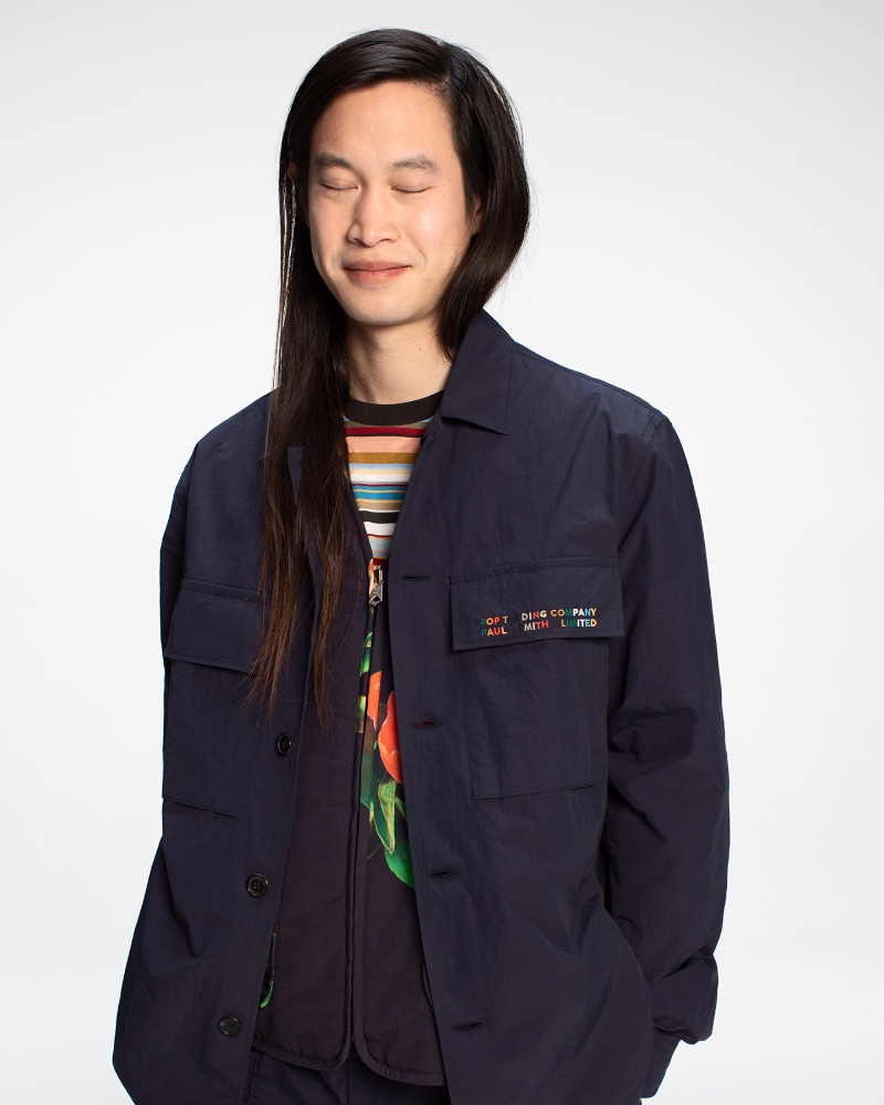 An Vo dons a navy patch-pocket overshirt with a tulip print reversible vest and stripe t-shirt from the Paul Smith + Pop Trading Company capsule collection. 