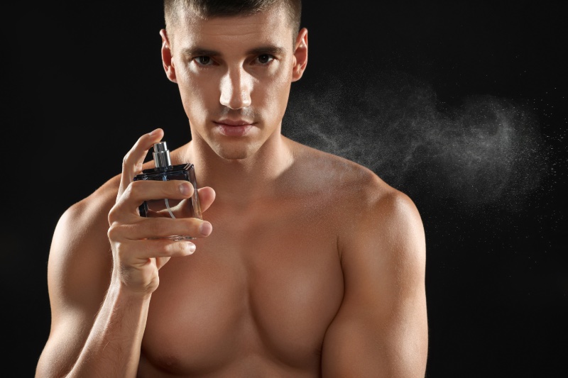 Shirtless Man Spraying Cologne Black Background