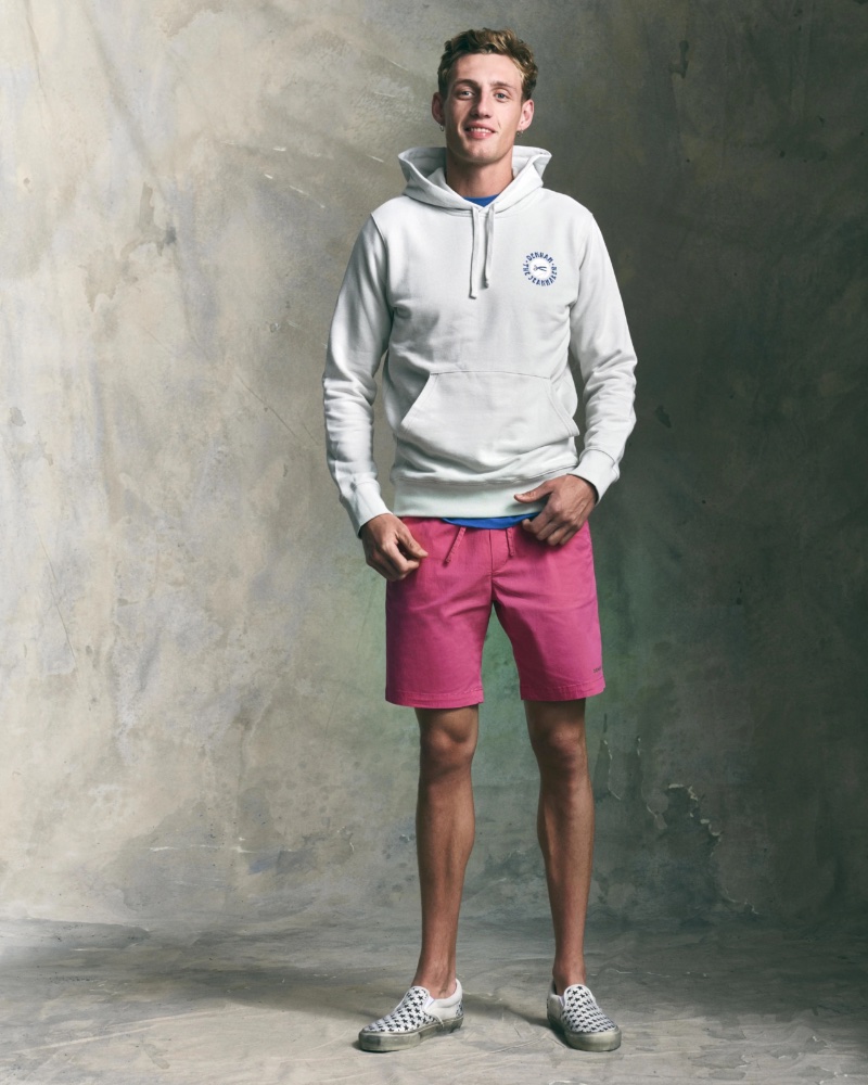 Aubrey O'Mahony sports pink shorts with a hoodie from DENHAM's summer 2023 collection.