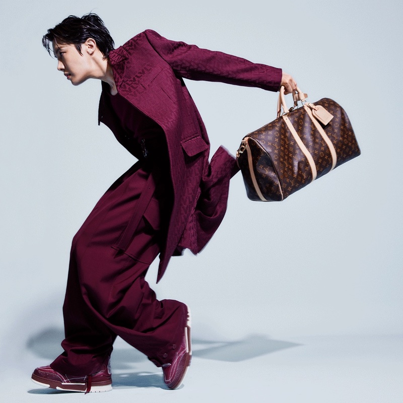 J-Hope sports a burgundy LV monogram coat with oversized cargo pants as he takes hold of a Louis Vuitton monogram keepall for the brand's newest advertising campaign.