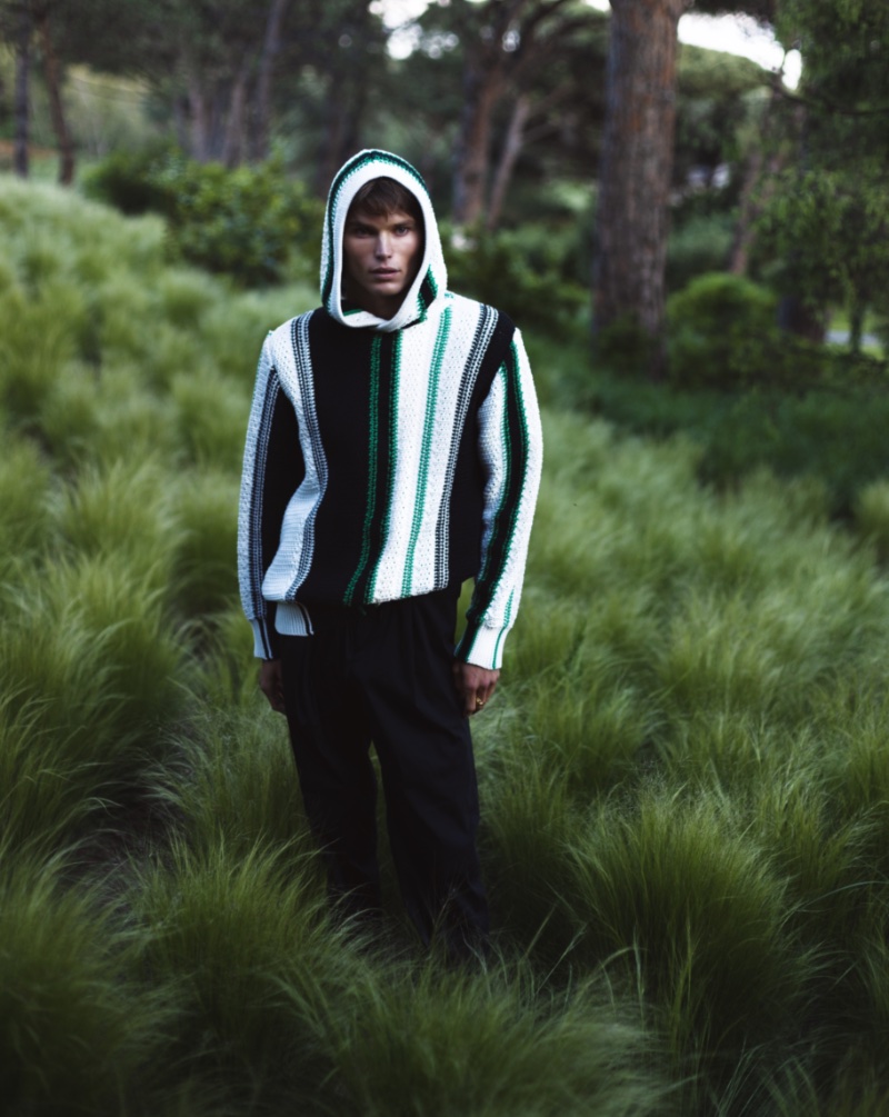 Australian model Jordan Barrett dons a striped knitted hooded sweatshirt with tapered trousers from his Orlebar Brown collaboration. 