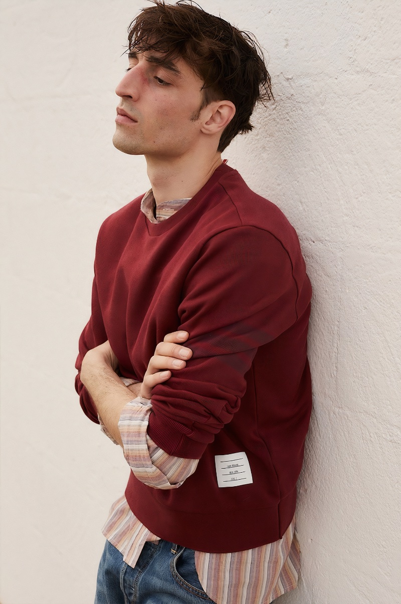 Embracing clay tones, Luca Jamal wears a Thom Browne crewneck with an Isabel Marant striped shirt and Re/Done jeans. 