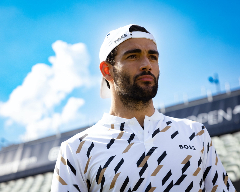 Sporting a backward cap, Matteo Berrettini showcases a houndstooth polo shirt from his BOSS capsule collection. 