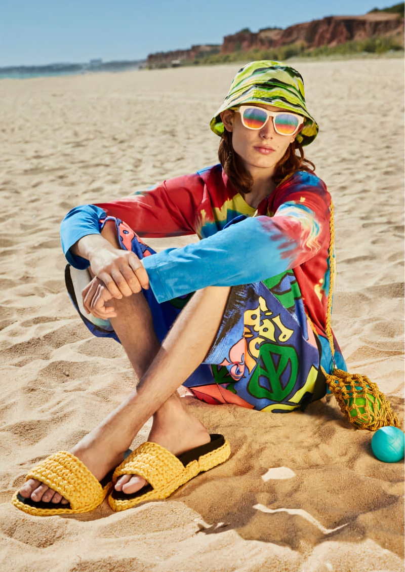 Mixing vibrant prints, Louis Joseph sports a Dries Van Noten bucket hat, Gucci GG1237SA sunglasses, and yellow N°21 sandals.