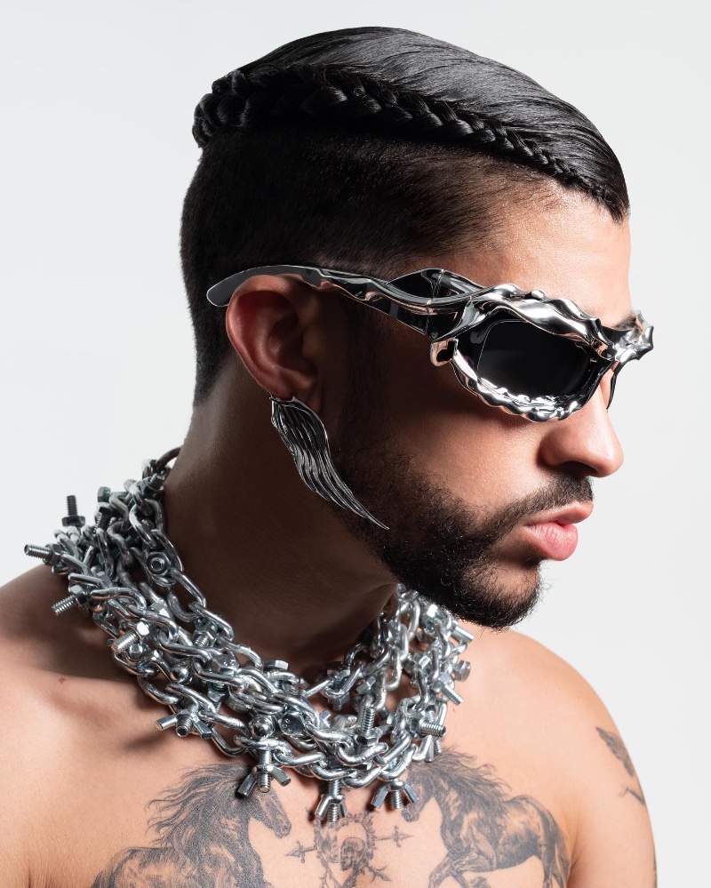 Delivering a side profile, Bad Bunny rocks Xtended Identity wing earrings with Ottolinger twisted sunglasses and Apt.1007 necklaces. 