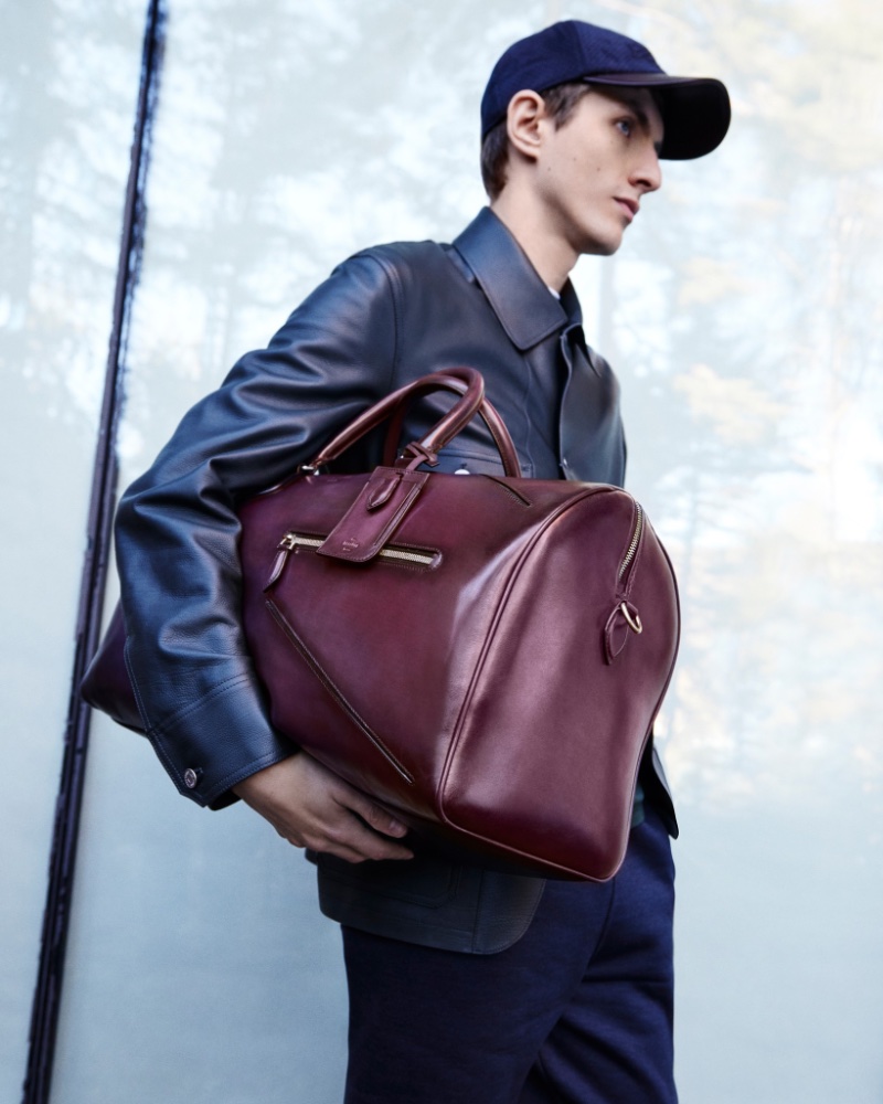 Taking hold of a leather carryall and wearing a sleek leather jacket, Henry Kitcher appears in Berluti's fall-winter 2023 campaign.