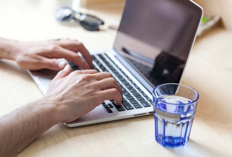 Glass of Water by Man Using Laptop Crop Glass of Water by Man Using Laptop Crop