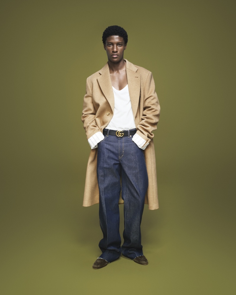 Aboubakar Konte wears a camel coat with pleated jeans for Gucci's fall-winter 2023 campaign. 