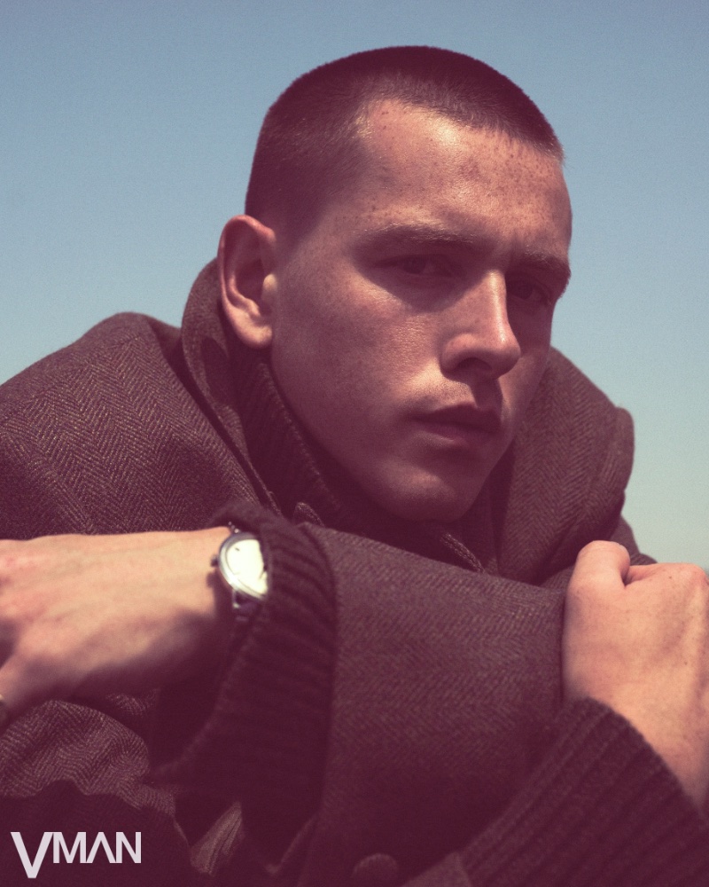 Harris Dickinson wears an oversized herringbone coat and cashmere turtleneck by Givenchy with an OMEGA De Ville Prestige watch.