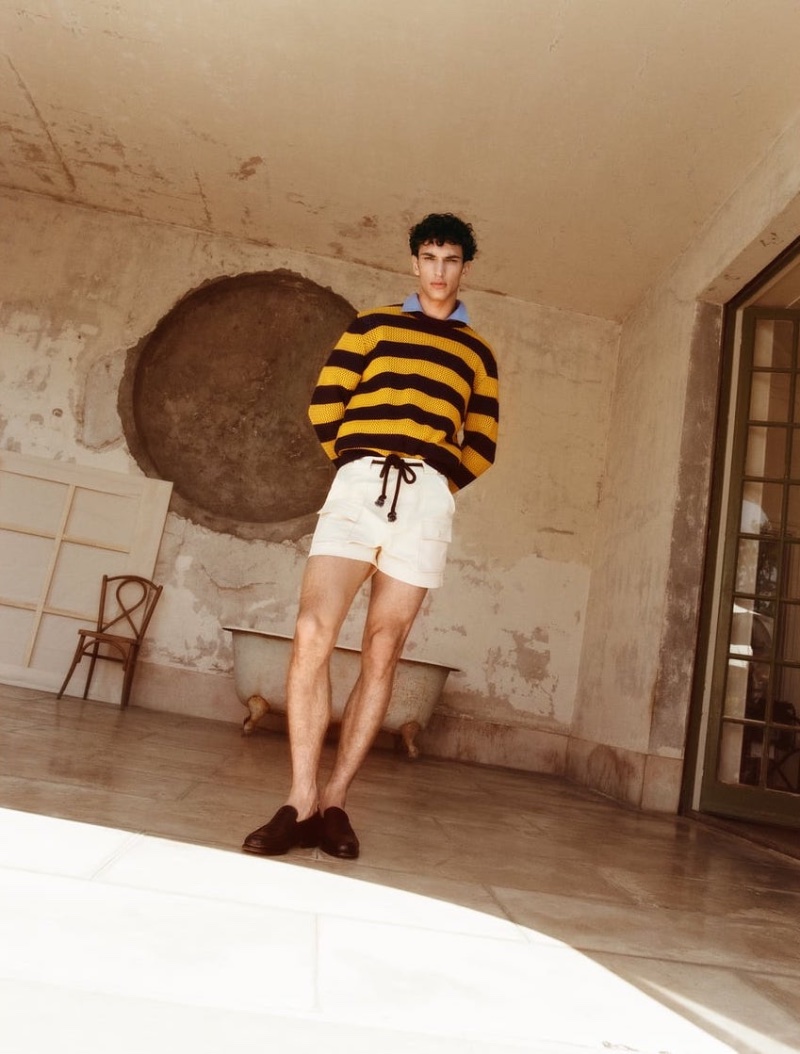A casual summer vision, Habib Masovic rocks a textured striped sweater with belted cargo shorts and glossy leather penny loafers.