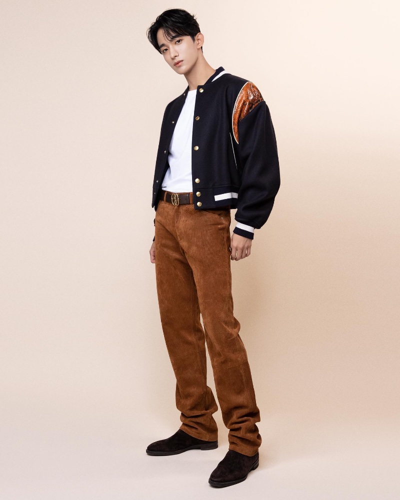Bally brand ambassador DK wears a pair of brown corduroy pants with a varsity jacket. 