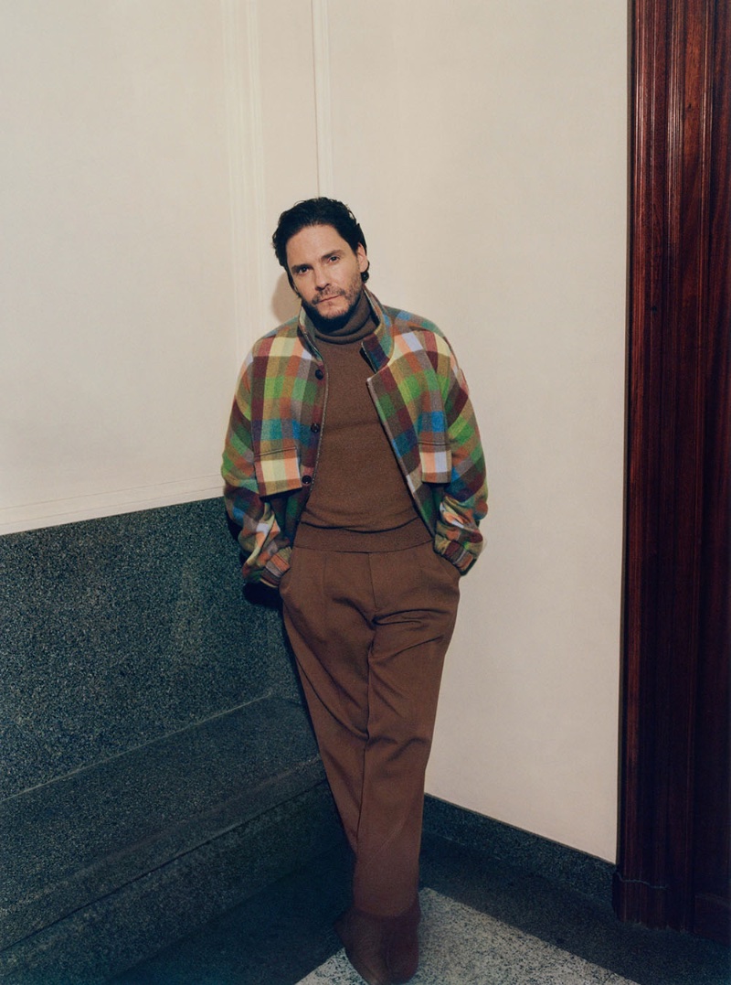 Daniel Brühl wears shades of brown underneath a colorful cashmere check jacket for the Zegna x The Elder Statesman fall-winter 2023 campaign. 