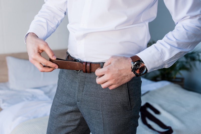 Man Putting on Brown Leather Belt