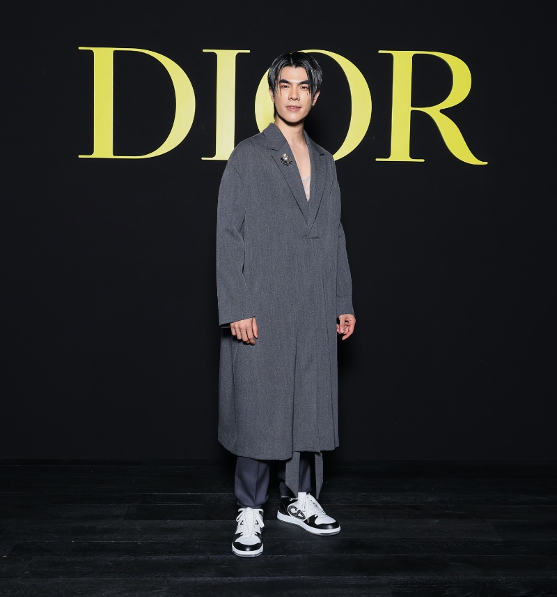 Embracing extra long proportions, Mile Phakphum Romsaithong wears a grey Dior Men poncho.