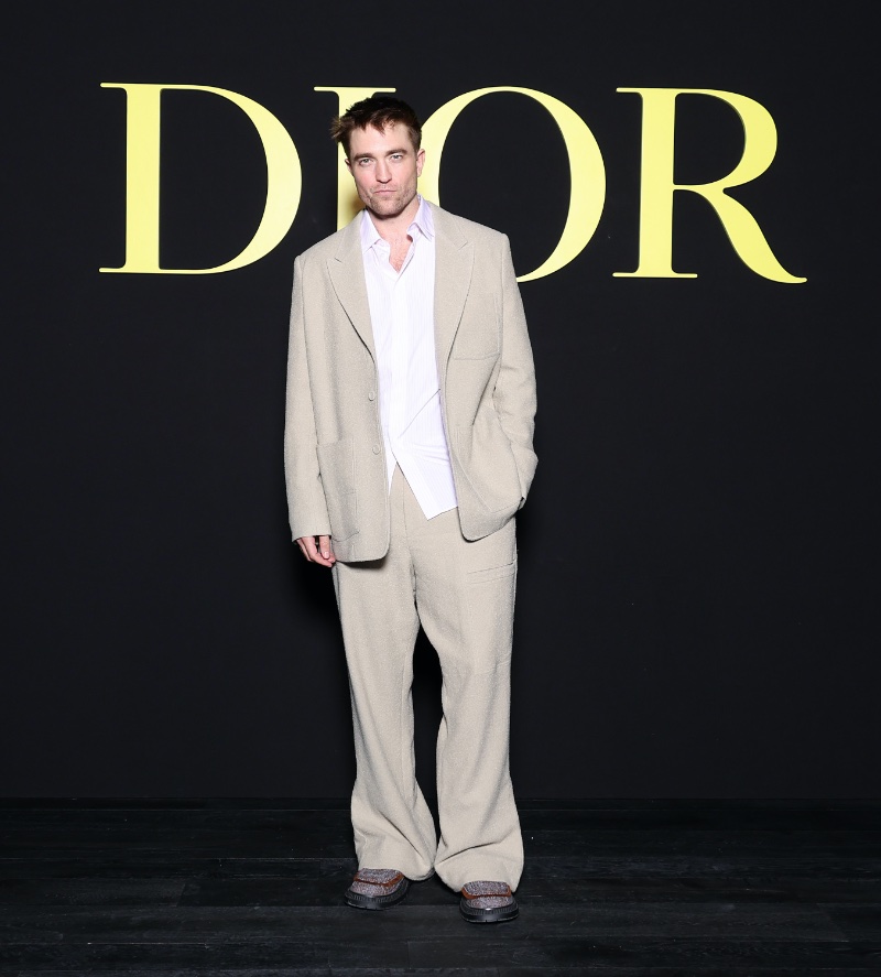 Dior ambassador Robert Pattinson wears a beige suit to the brand's spring-summer 2024 women's show. 