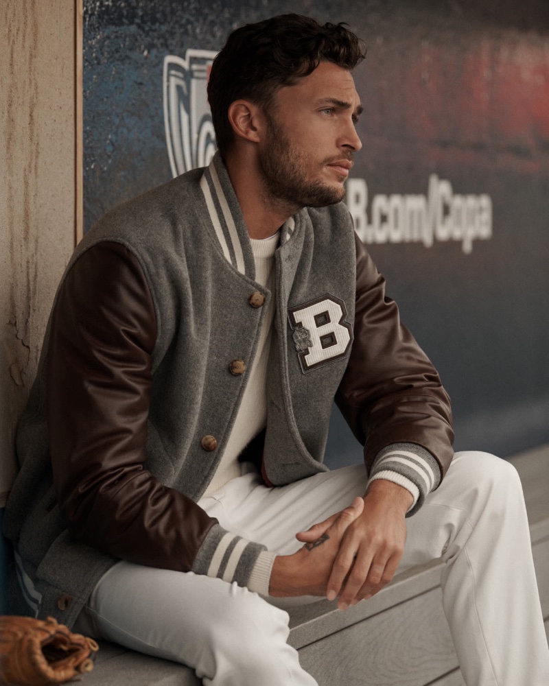Embracing baseball-inspired style, Harvey Haydon wears a handcrafted bomber jacket over an English rib knit sweater with Gabardine garment dyed trousers.