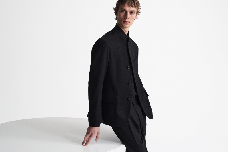 Model Leon Dame sports a black 4-button wool and cashmere jacket with pleated trousers for Corneliani's fall-winter 2023 campaign.