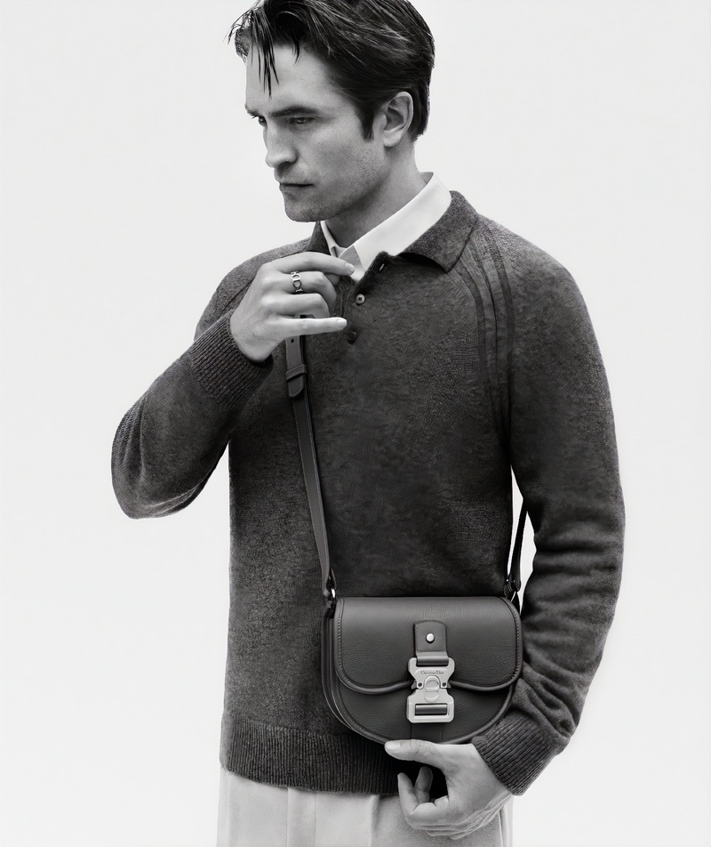 Wearing a long-sleeve knit polo and the Dior Gallop shoulder bag, Robert Pattinson fronts the Dior New Icons advertisement. 