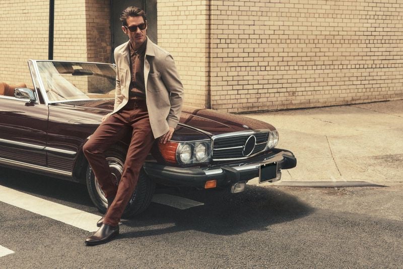 Classic meets contemporary as Domenique Melchior leans on a vintage car, showcasing 34 Heritage's holiday 2023 collection.