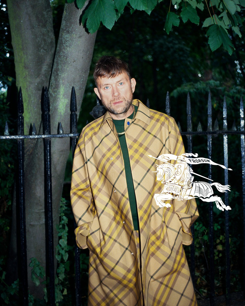 Damon Albarn commands attention in a classic checkered Burberry coat, bringing a touch of Brit-pop edge to the spring 2024 campaign.