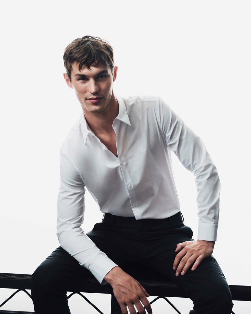 Kit Butler wears classic style in a crisp white Calvin Klein shirt paired with elegant black trousers.