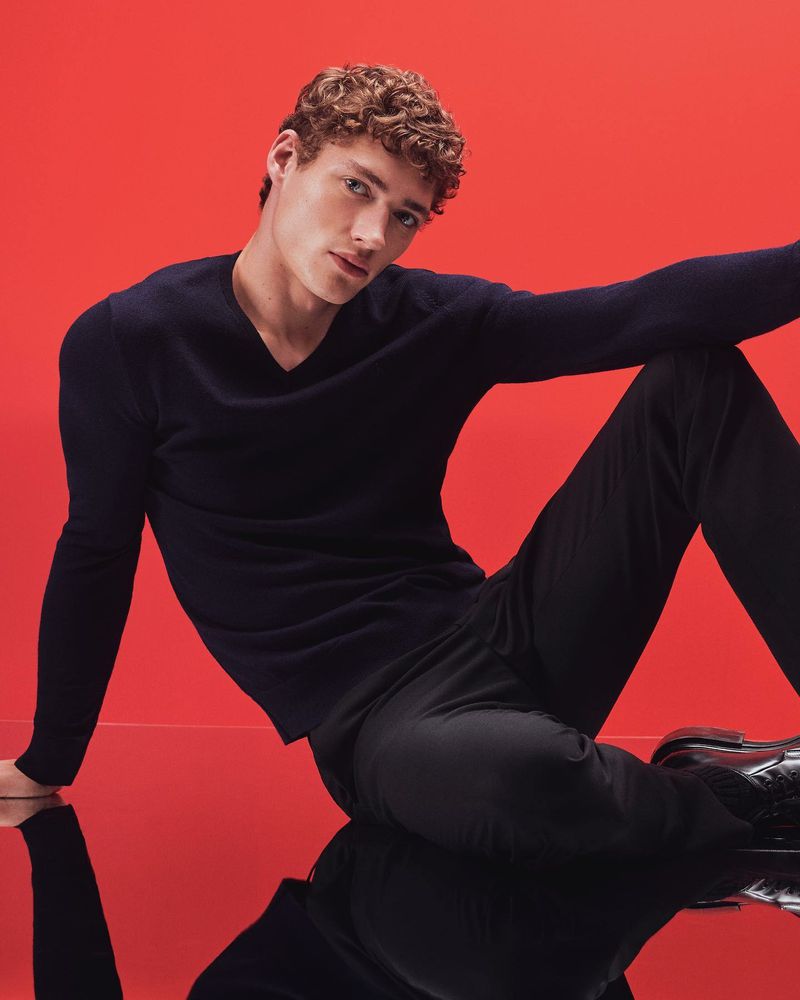 Top model Valentin Humbroich strikes a pose wearing a navy Calvin Klein v-neck sweater and black trousers.