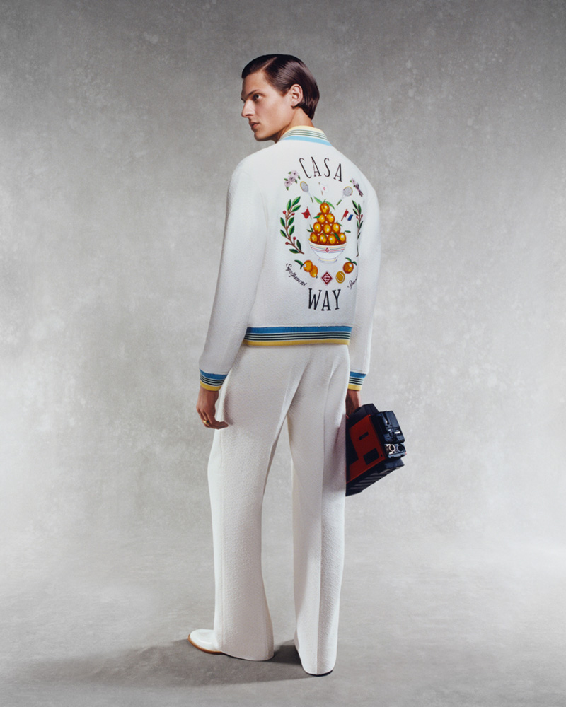 Valentin Caron turns his back to show off the intricate embroidery of a Casablanca pre-spring 2024 jacket paired with pristine white trousers for a look that's both fresh and refined.