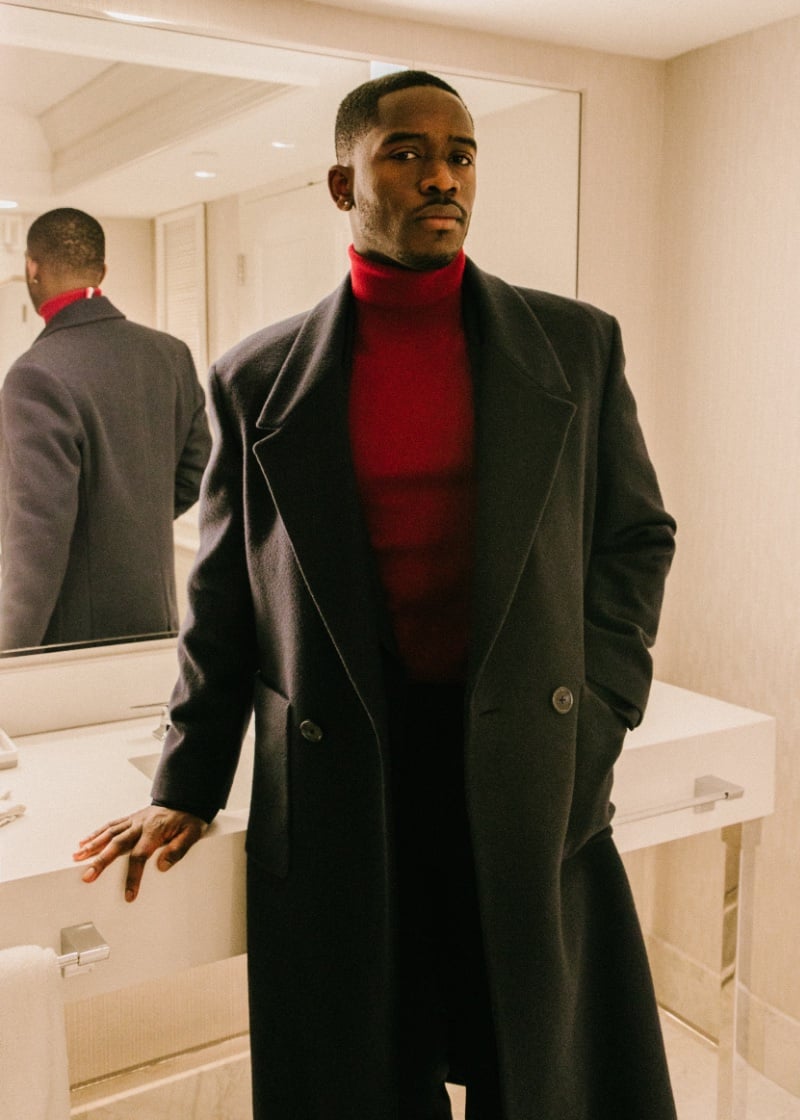 For the Qualifying event, Damson Idris layers in luxury with a wool blend coat over a turtleneck and a long blazer, complemented by tailored wool trousers.