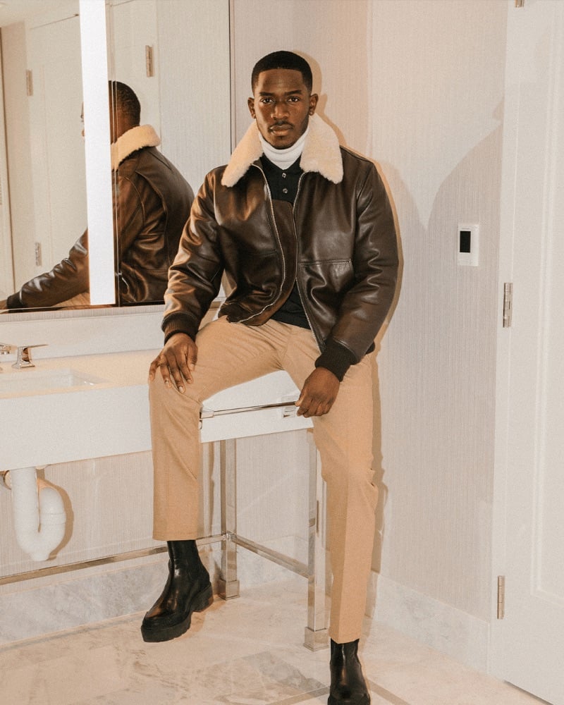 Damson Idris exemplifies jet-set sophistication in a Tommy Hilfiger bomber jacket, a turtleneck, and trousers while en route to Las Vegas.