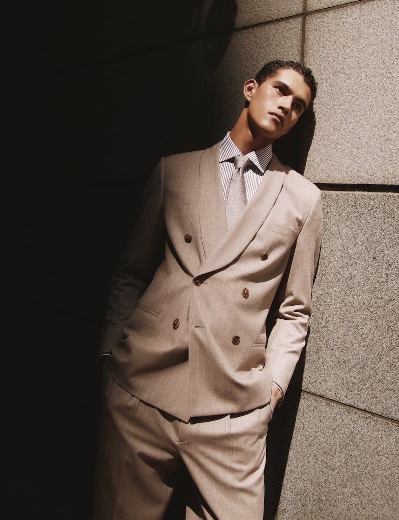 Bodhi Heeck stands poised in a tailored Giorgio Armani beige double-breasted suit.